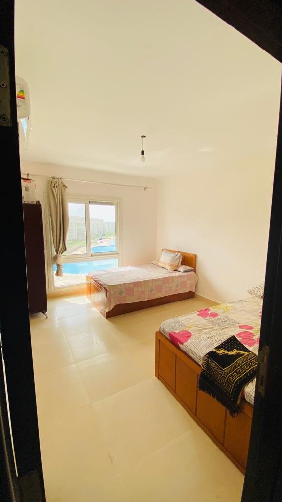 3-bedroom-chalet-for-sale-in-egypt-6 غرفة نوم بسرير ونافذة تطل على حمام السباحة في أروما ريزورت