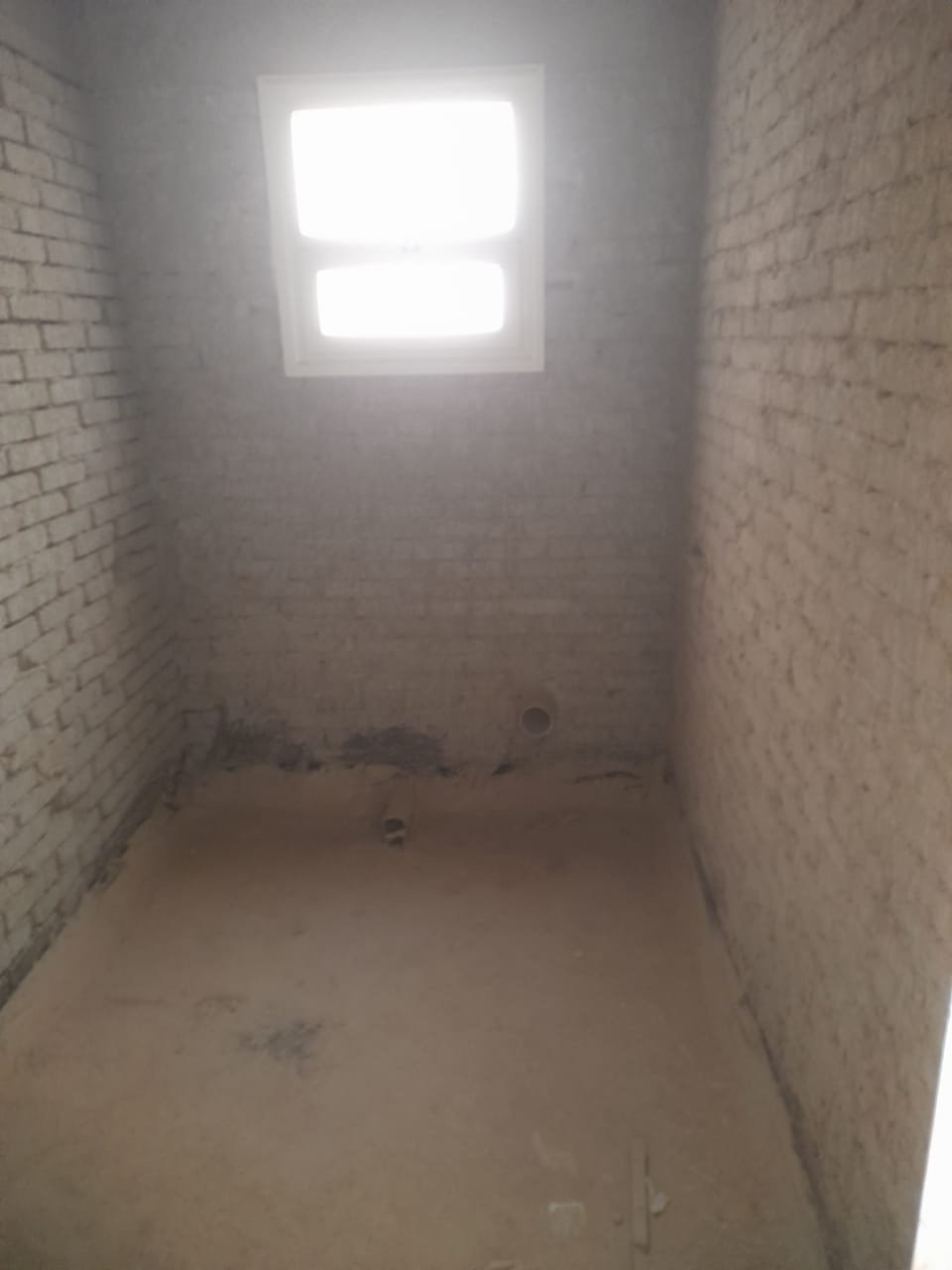 Small unfinished room with block walls and a high window - penthouse in Green House, 5th Settlement
