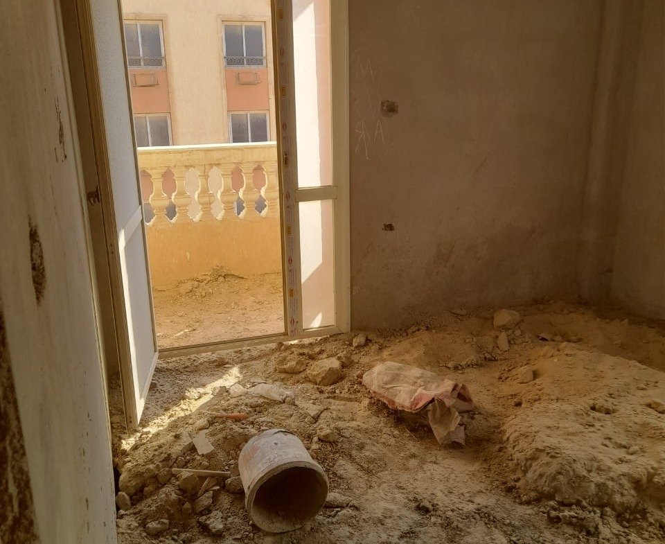 Unfinished room with a balcony door and a pipe on a sandy floor - penthouse in Green House, 5th Settlement