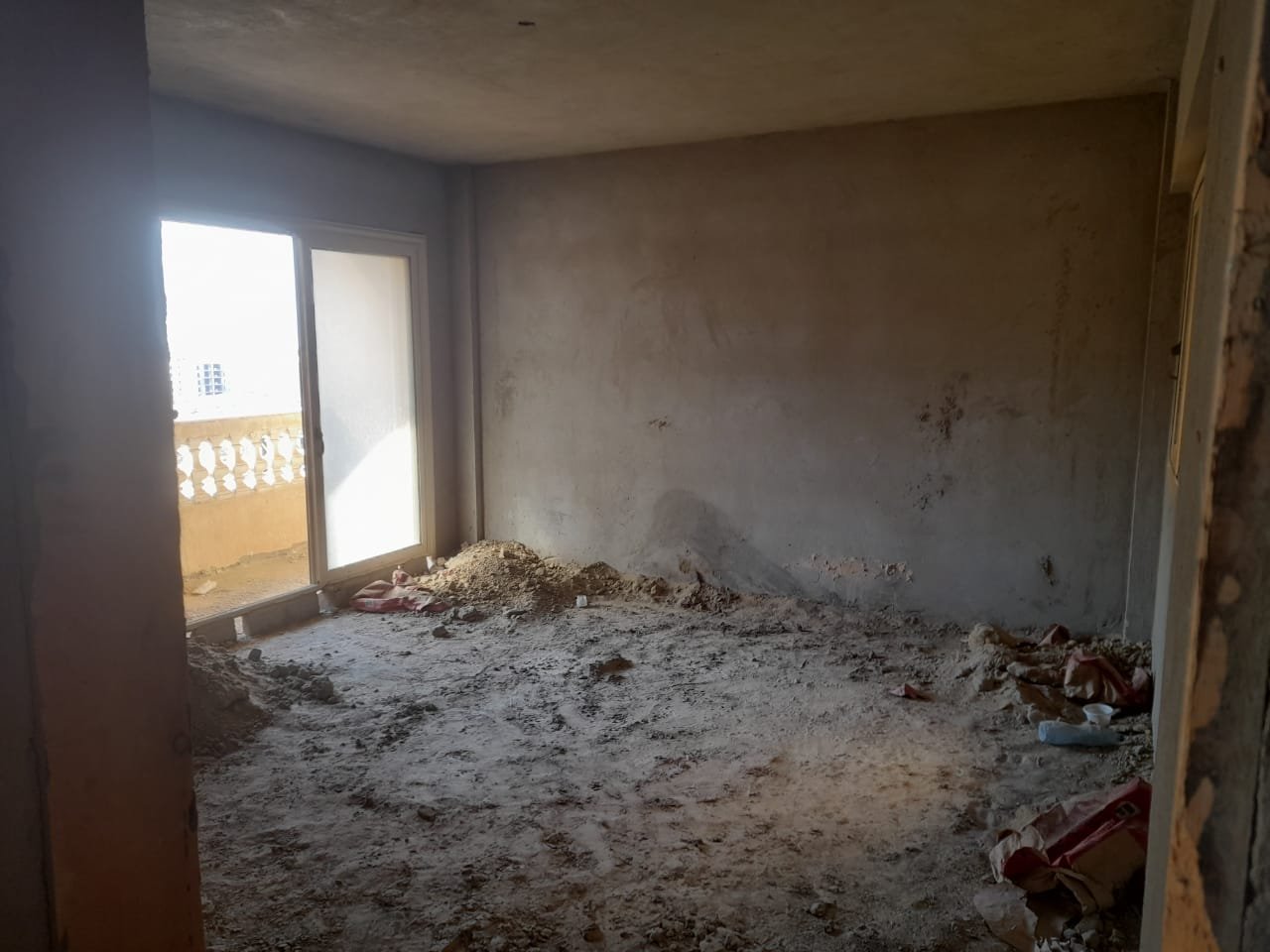 Bare room with a balcony door and rubble on the floor - penthouse in Green House, 5th Settlement