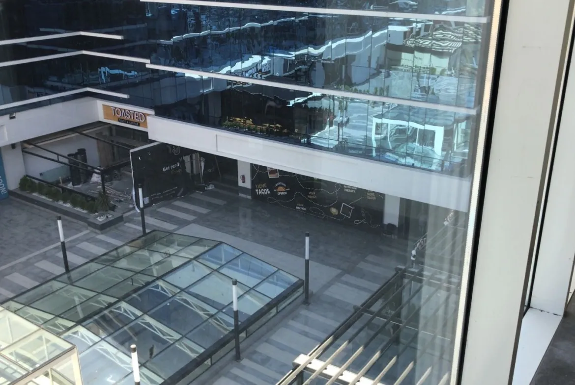 View down into a glass-roofed mall atrium with shopfronts - unit in Marassi