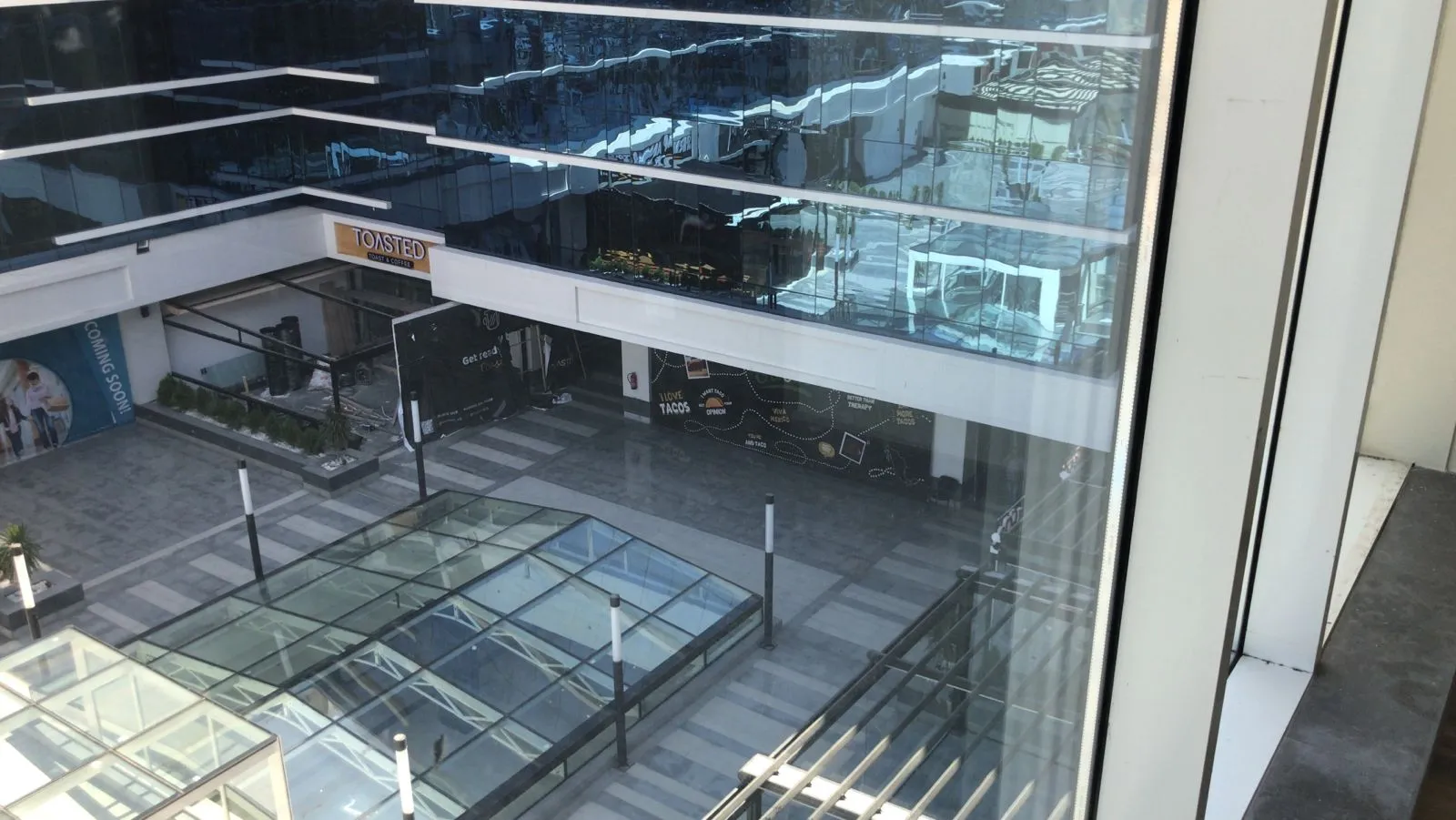 View down into a glass-roofed mall atrium with shopfronts - unit in Marassi