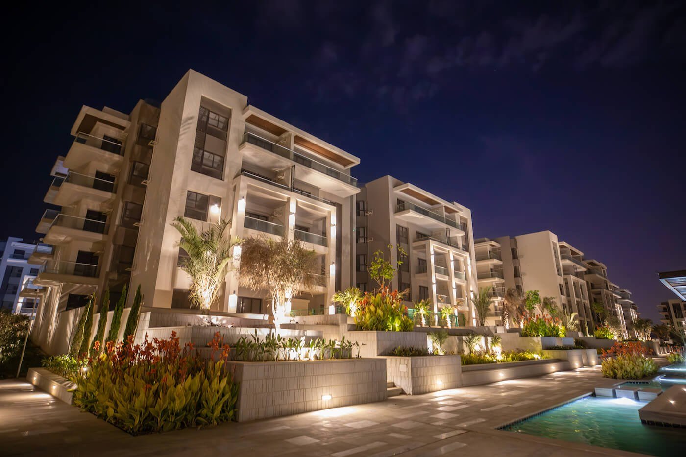 Residential buildings at night, The Address East, New Cairo - general project photo for apartment for sale | مبانٍ سكنية ليلًا، ذا أدريس إيست، القاهرة الجديدة - صورة عامة للمشروع لشقة للبيع