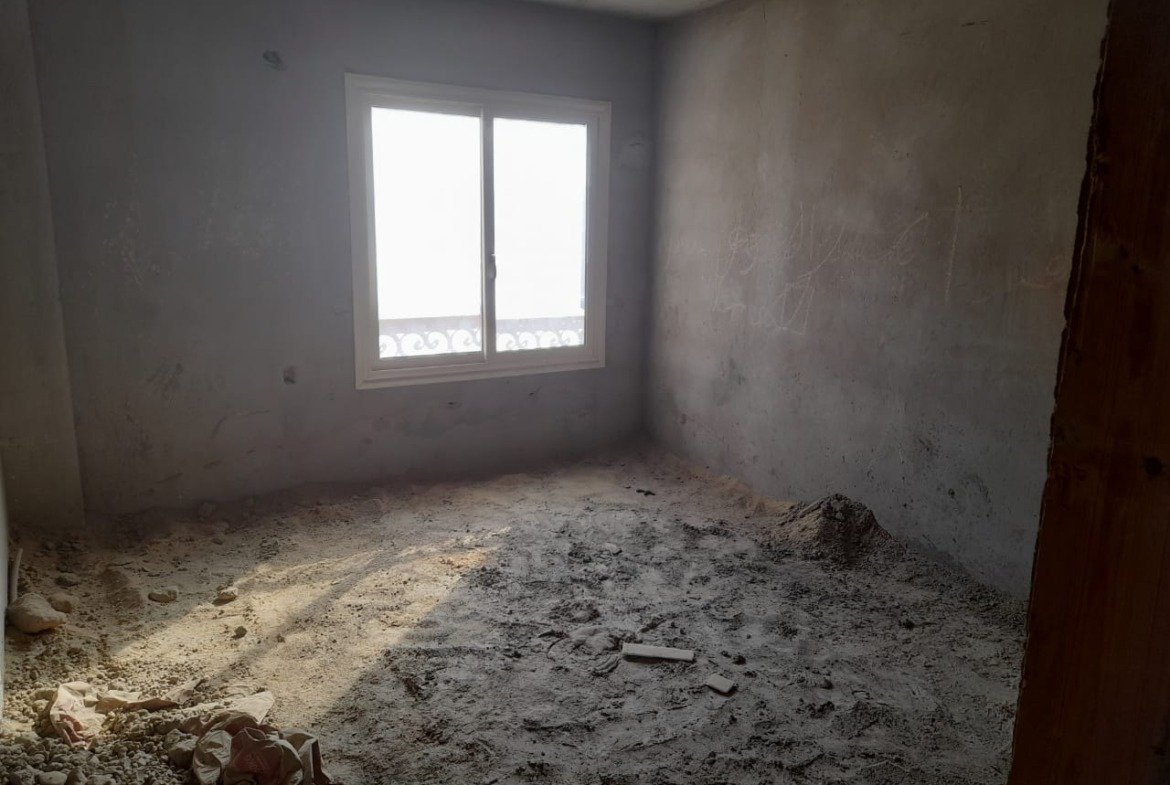 Bare concrete room with a window and a dusty floor - penthouse in Green House, 5th Settlement
