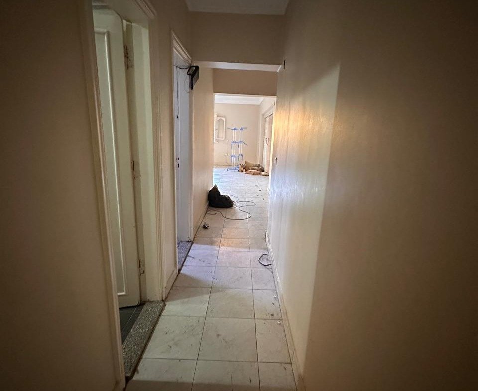 Dim hallway with a tiled floor and an open door - apartment in Sahafeen Compound, New Cairo