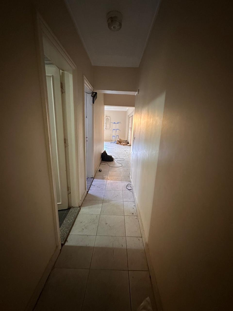 Dim hallway with a tiled floor and an open door - apartment in Sahafeen Compound, New Cairo