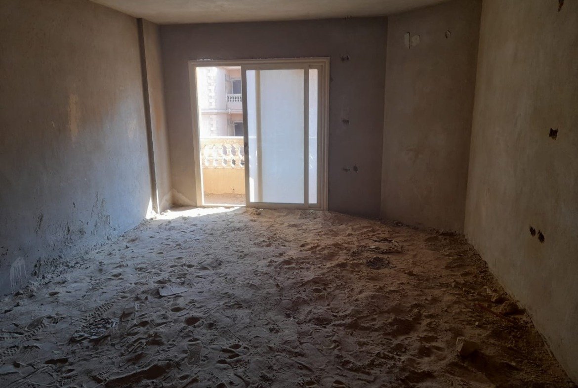 Unfinished room with a balcony door lit by sunlight - penthouse in Green House, 5th Settlement