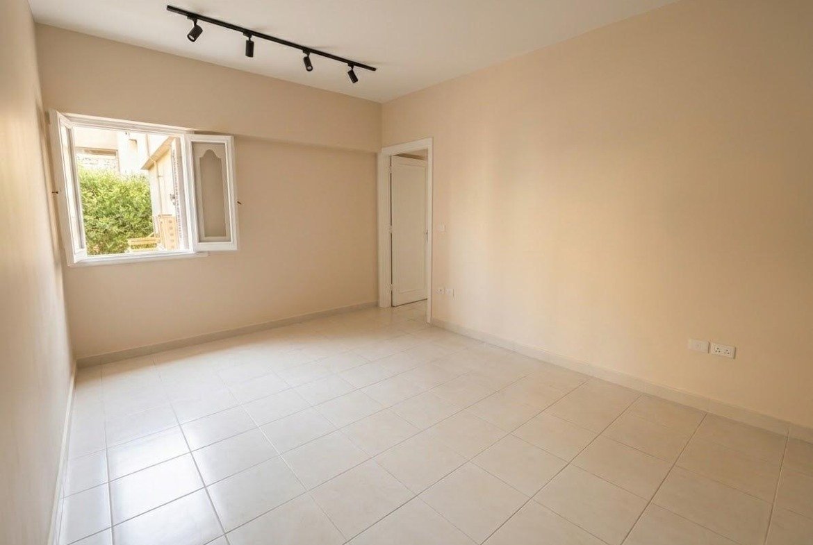 Empty room with beige walls, a window and a track light - apartment in Sahafeen Compound, New Cairo