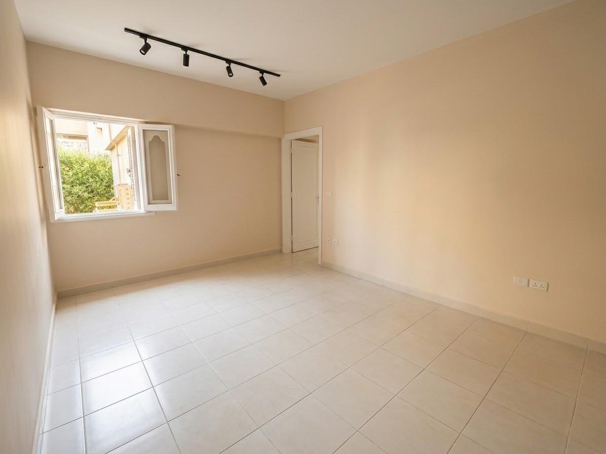 Empty room with beige walls, a window and a track light - apartment in Sahafeen Compound, New Cairo