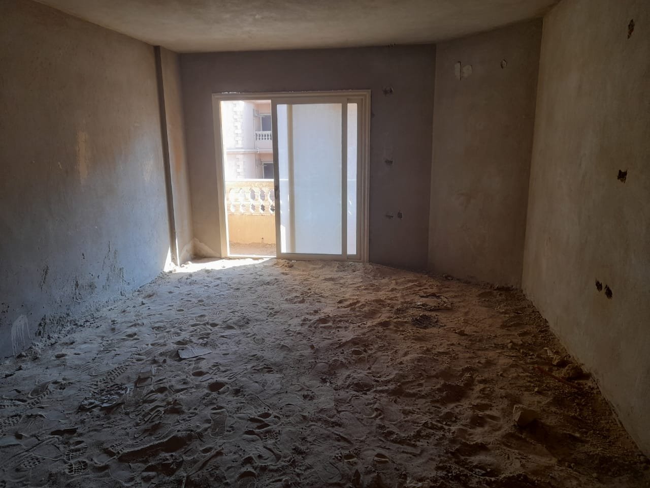Unfinished room with a balcony door lit by sunlight - penthouse in Green House, 5th Settlement