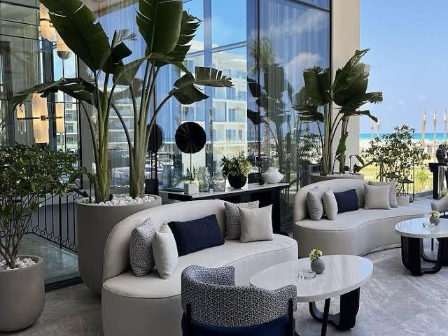 Lounge seating beside tall windows and plants in Marassi, North Coast
