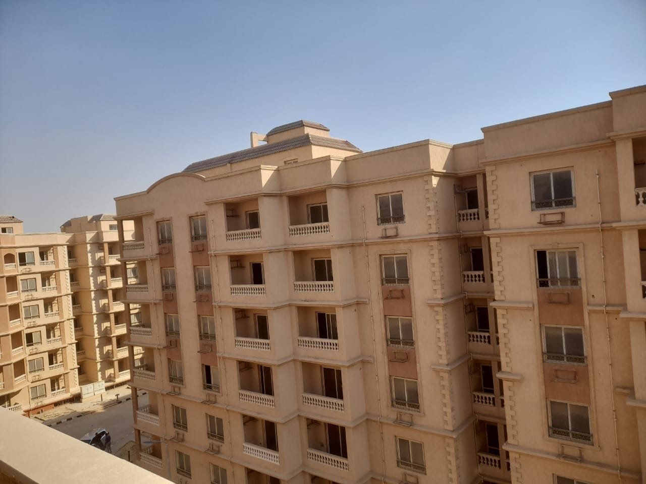 Beige apartment building with many balconies against a clear sky - penthouse in Green House, 5th Settlement