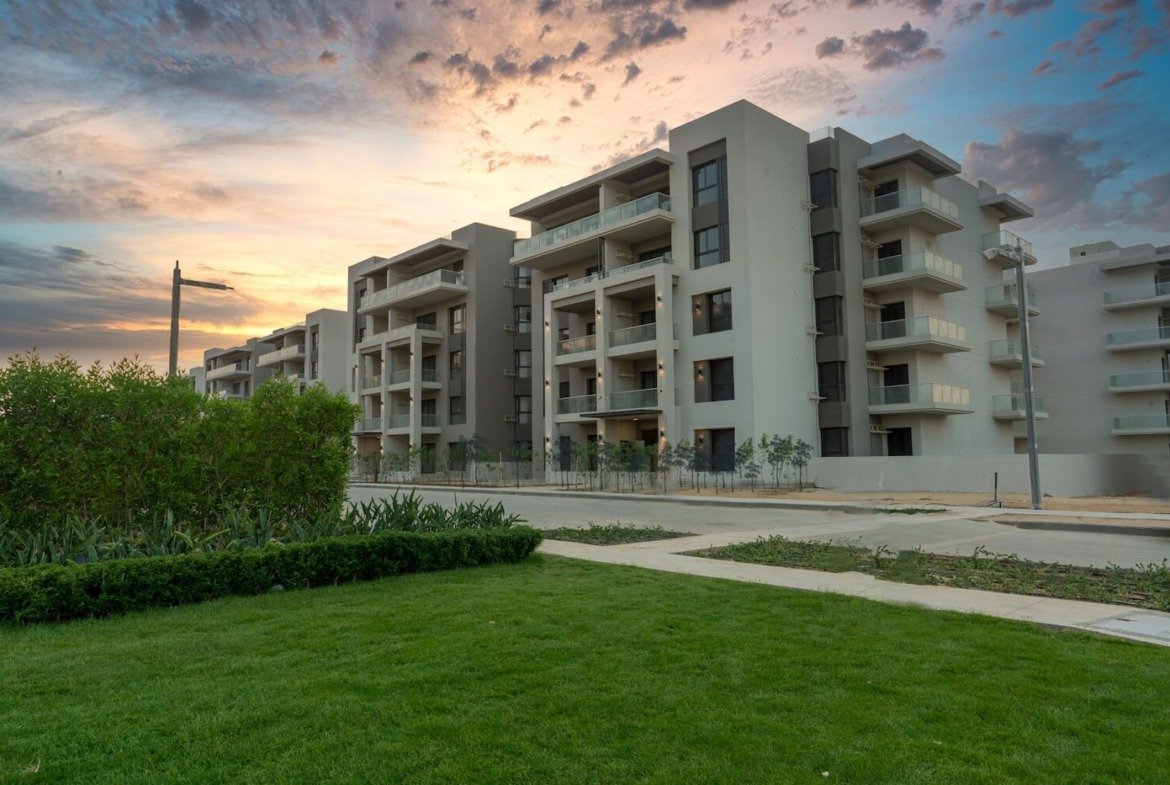 Buildings and gardens at sunset, The Address East, New Cairo - general project photo for apartment for sale | مبانٍ وحدائق وقت الغروب، ذا أدريس إيست، القاهرة الجديدة - صورة عامة للمشروع لشقة للبيع