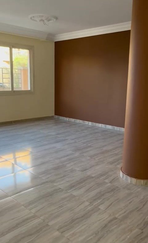 Large empty room with a brown column and a wood-look floor - apartment in 2nd District, 5th Settlement