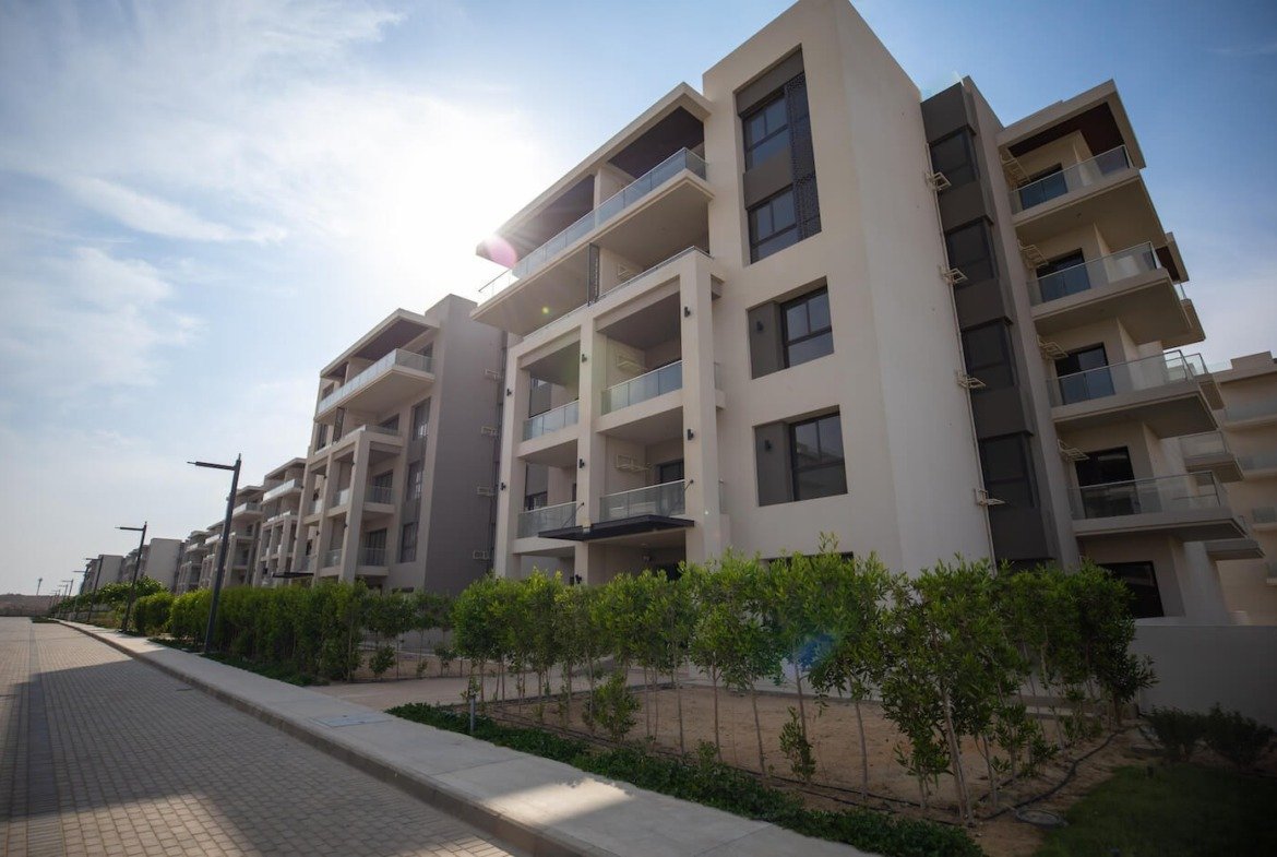 Residential buildings and landscaped walkway, The Address East, New Cairo - general project photo for apartment for sale | مبانٍ سكنية وممر بين الحدائق، ذا أدريس إيست، القاهرة الجديدة - صورة عامة للمشروع لشقة للبيع