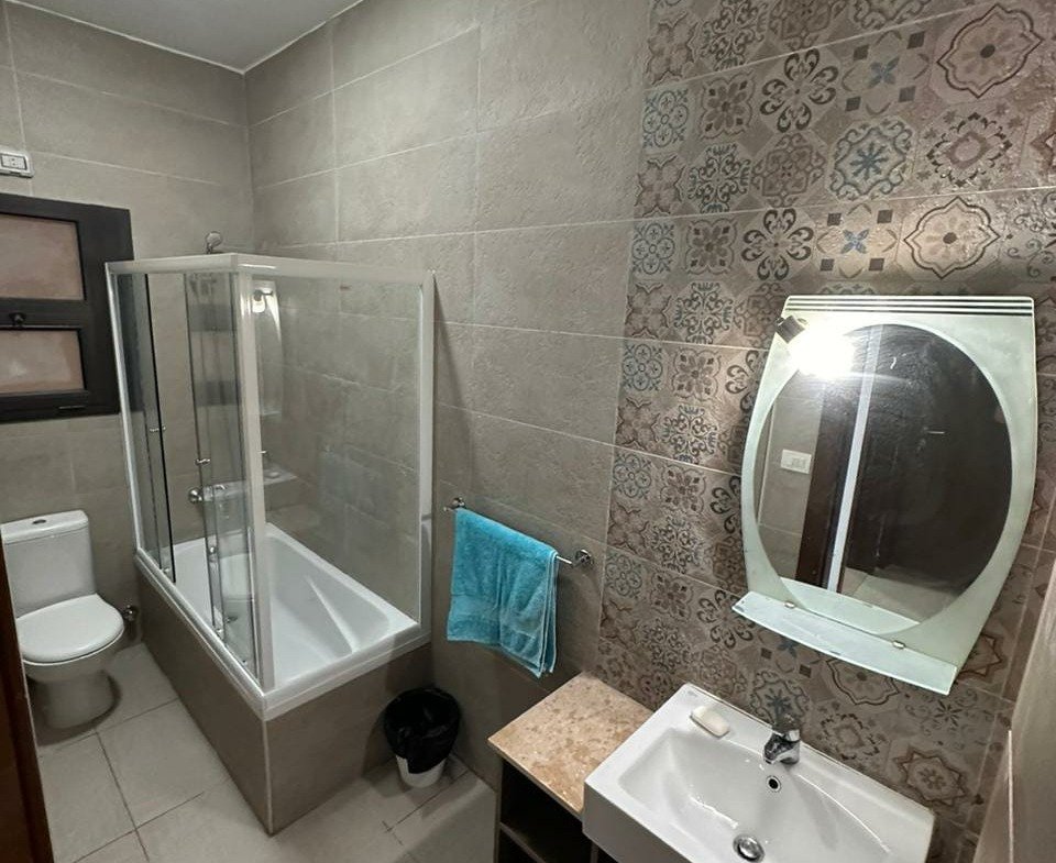 Bathroom with glass shower and round mirror - apartment in Golden Square, Fifth Square, New Cairo