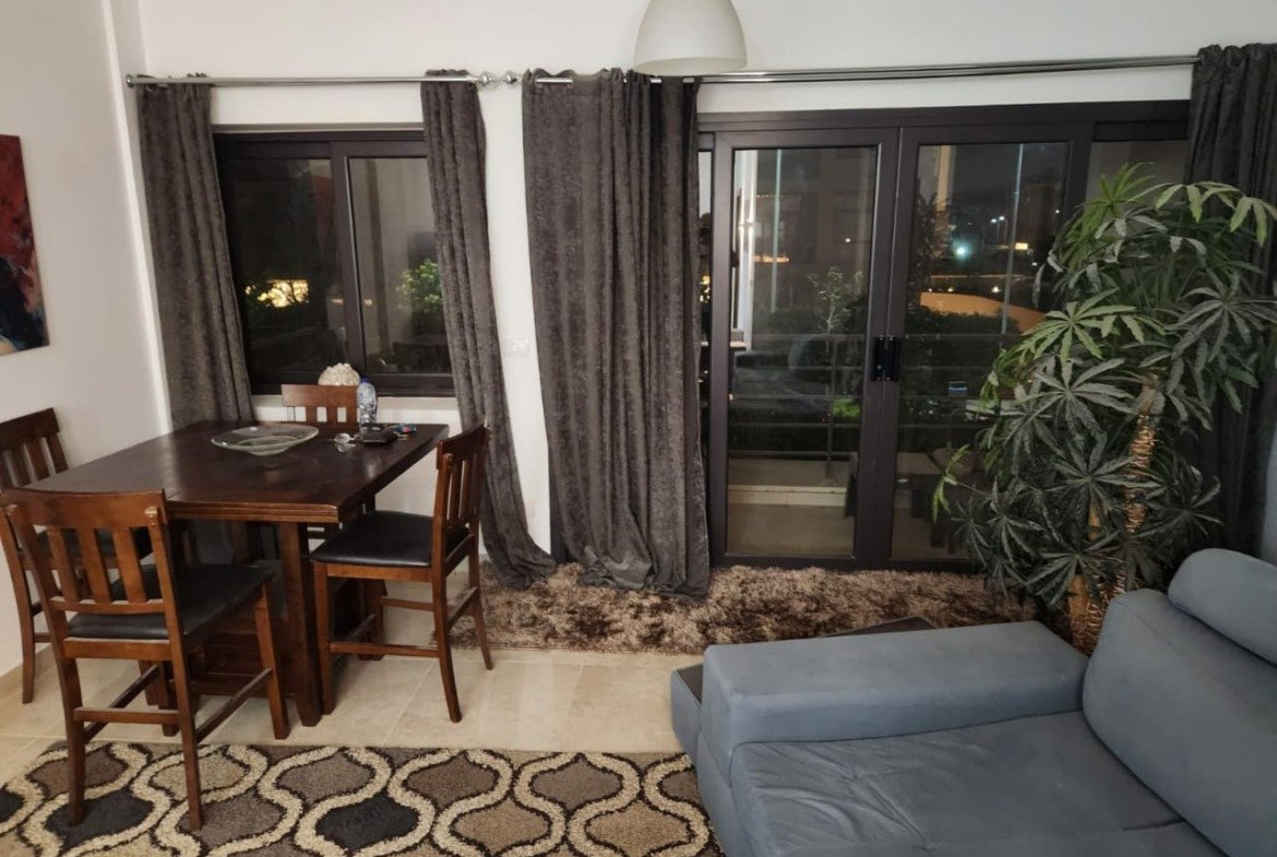 Dining table and sofa beside the balcony doors - apartment in Golden Square, Fifth Square, New Cairo