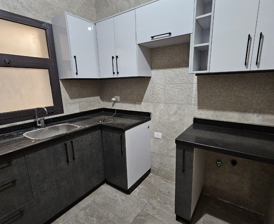 Kitchen with white cabinets and black counter - studio in Fifth Square, New Cairo