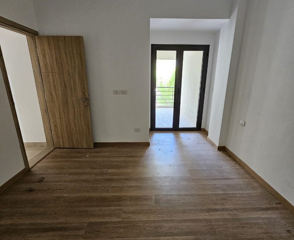 Empty room with balcony door and wooden floor - studio in Fifth Square, New Cairo
