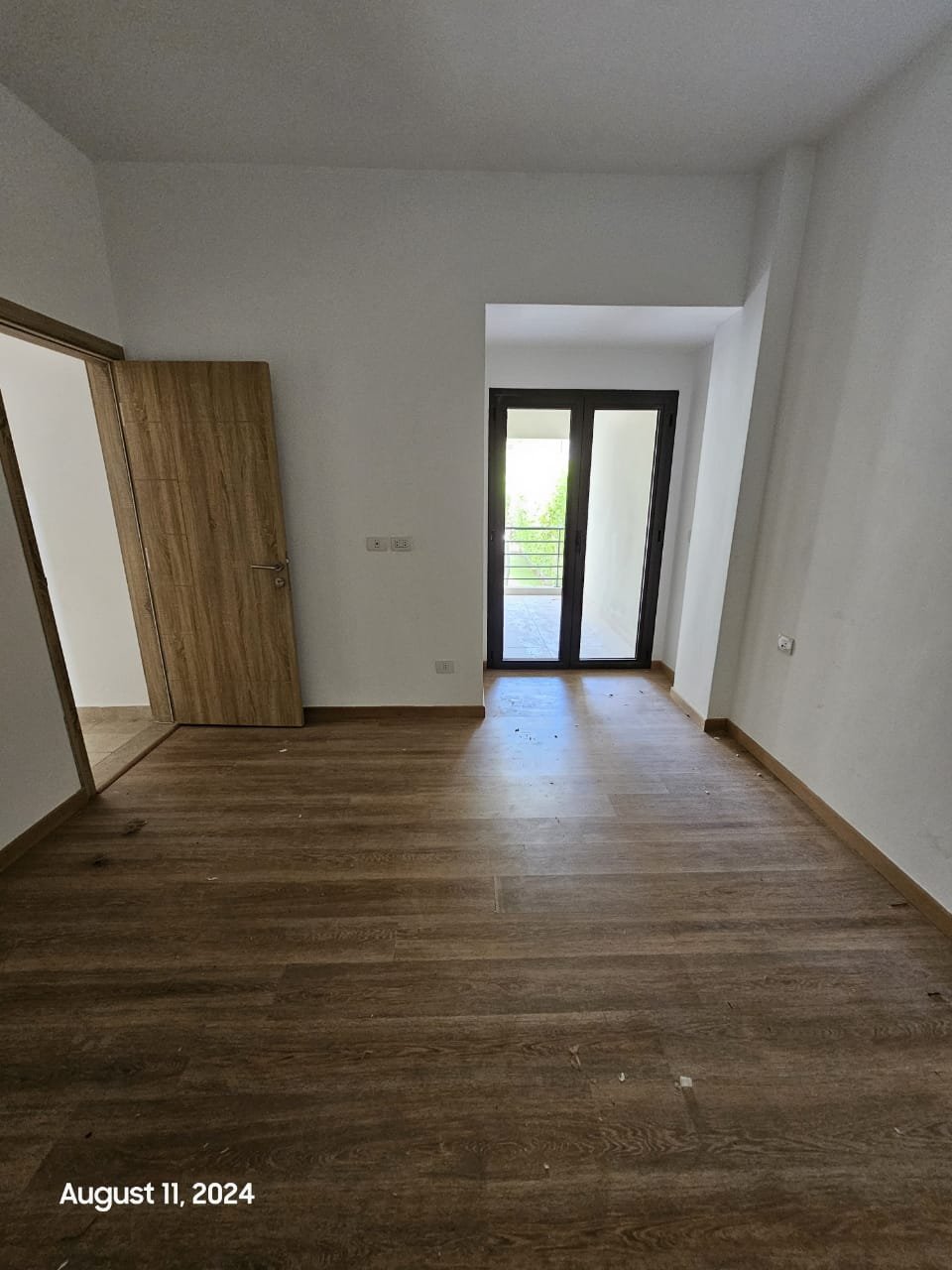 Empty room with balcony door and wooden floor - studio in Fifth Square, New Cairo