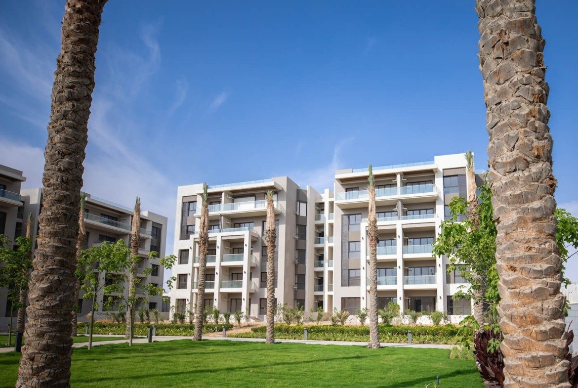 Gardens and palms beside apartment buildings, The Address East, New Cairo - general project photo for apartment for sale | حدائق ونخيل بجوار المباني السكنية، ذا أدريس إيست، القاهرة الجديدة - صورة عامة للمشروع لشقة للبيع
