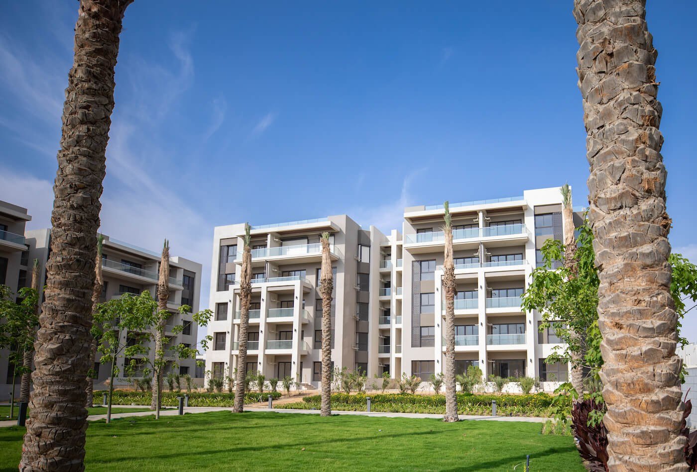 Gardens and palms beside apartment buildings, The Address East, New Cairo - general project photo for apartment for sale | حدائق ونخيل بجوار المباني السكنية، ذا أدريس إيست، القاهرة الجديدة - صورة عامة للمشروع لشقة للبيع