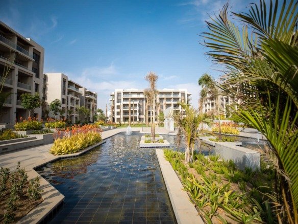 Water features and gardens between buildings, The Address East, New Cairo - general project photo for apartment for sale | مساحات مائية وحدائق بين المباني، ذا أدريس إيست، القاهرة الجديدة - صورة عامة للمشروع لشقة للبيع