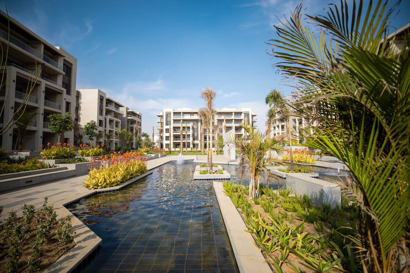 Water features and gardens between buildings, The Address East, New Cairo - general project photo for apartment for sale | مساحات مائية وحدائق بين المباني، ذا أدريس إيست، القاهرة الجديدة - صورة عامة للمشروع لشقة للبيع