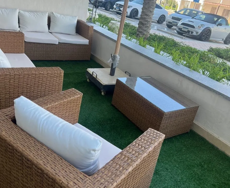 بلكونة بكنبة روطان ونجيلة صناعية ومظلة - شاليه في مراسي فايا، الساحل الشمالي