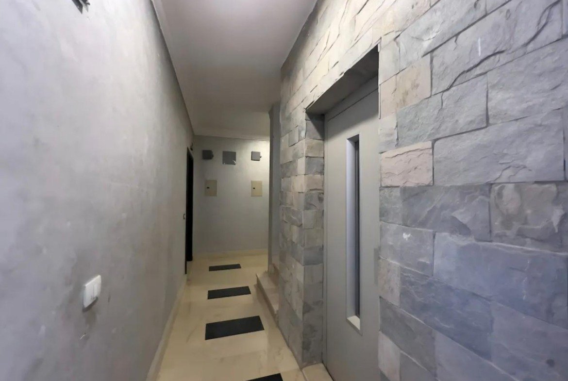 Corridor with a stone-clad wall and dark floor mats - apartment in Akoya, New Cairo