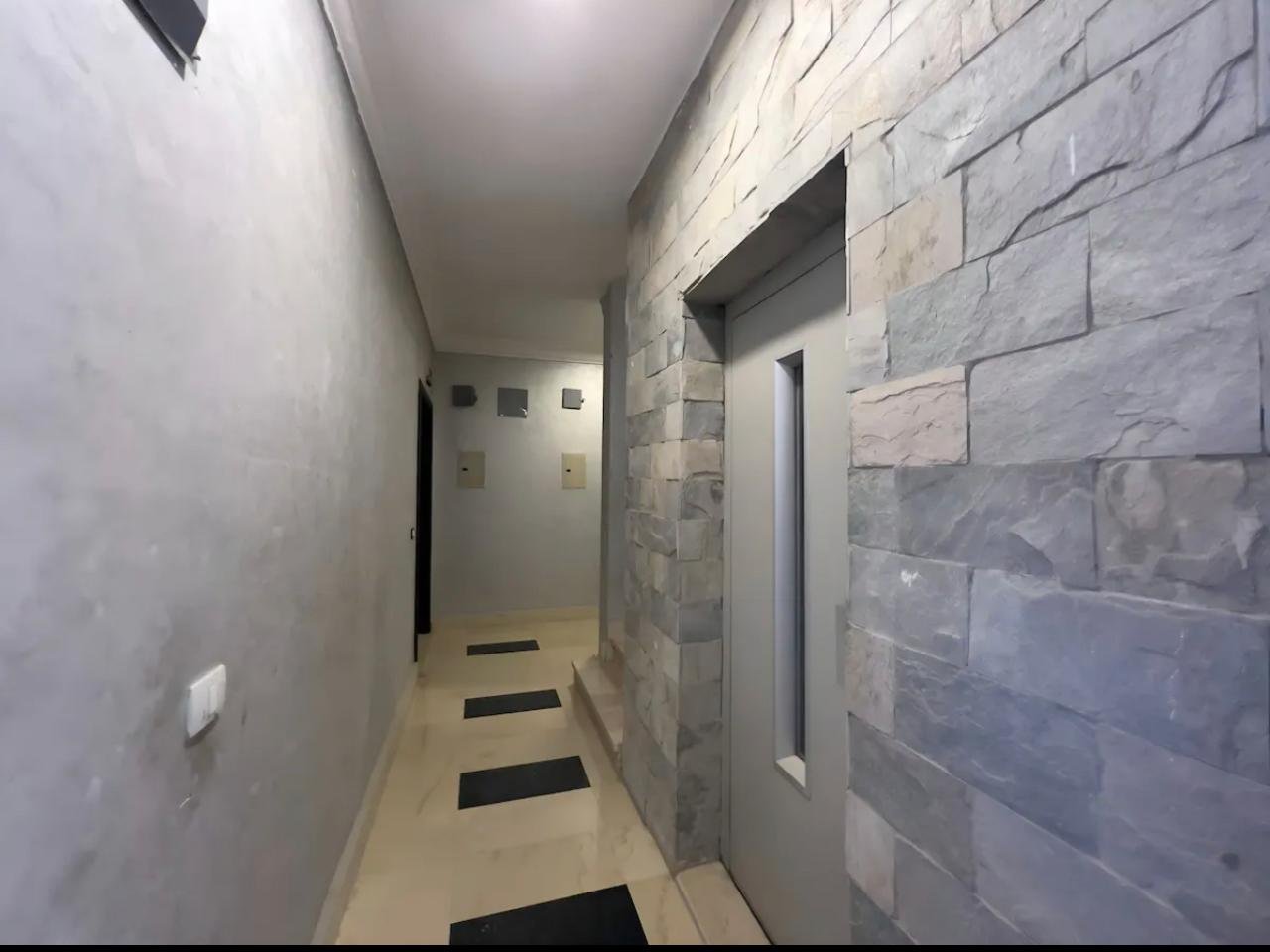 akoya-513-12 Corridor with a stone-clad wall and dark floor mats - apartment in Akoya, New Cairo