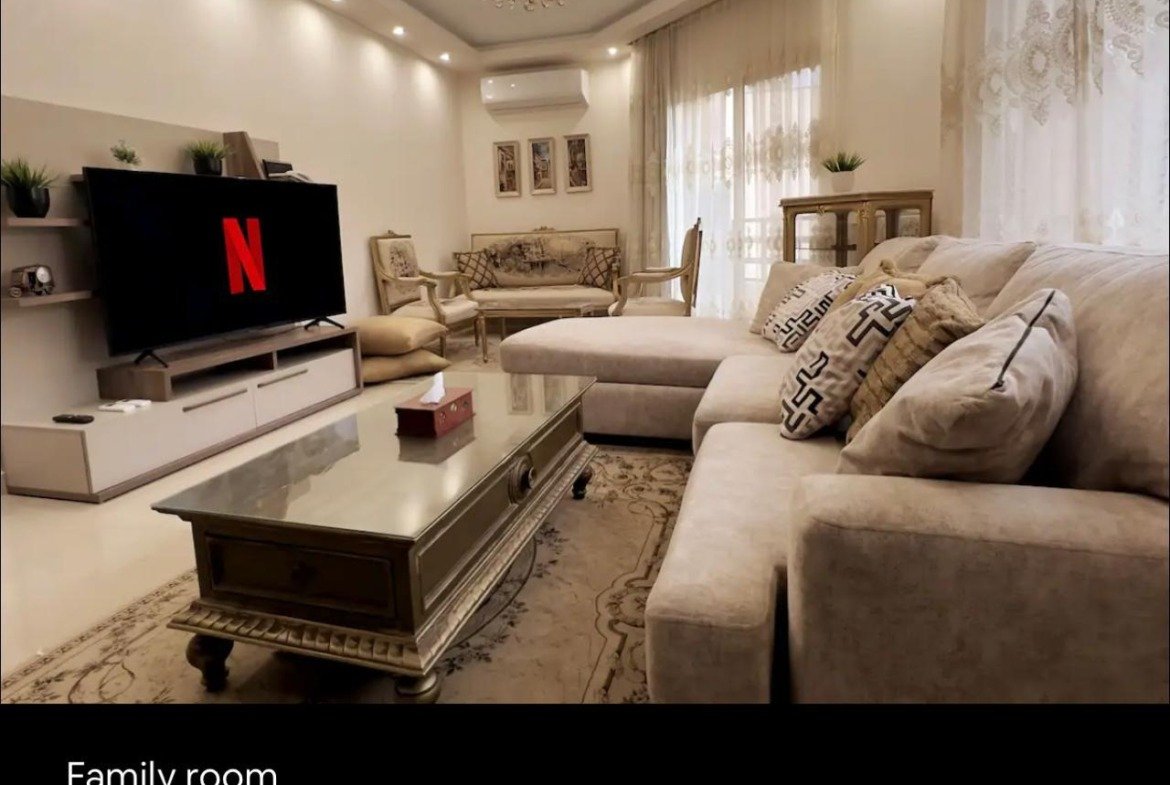 Family living room with a TV unit and a beige sofa - apartment in Akoya, New Cairo