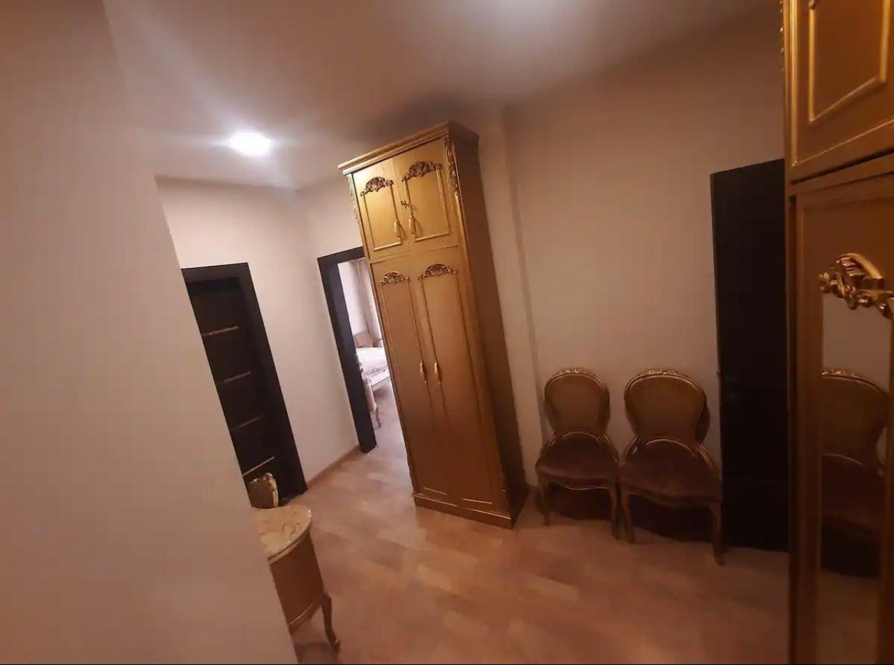 akoya-513-26 Bedroom with a wooden wardrobe and two chairs - apartment in Akoya, New Cairo