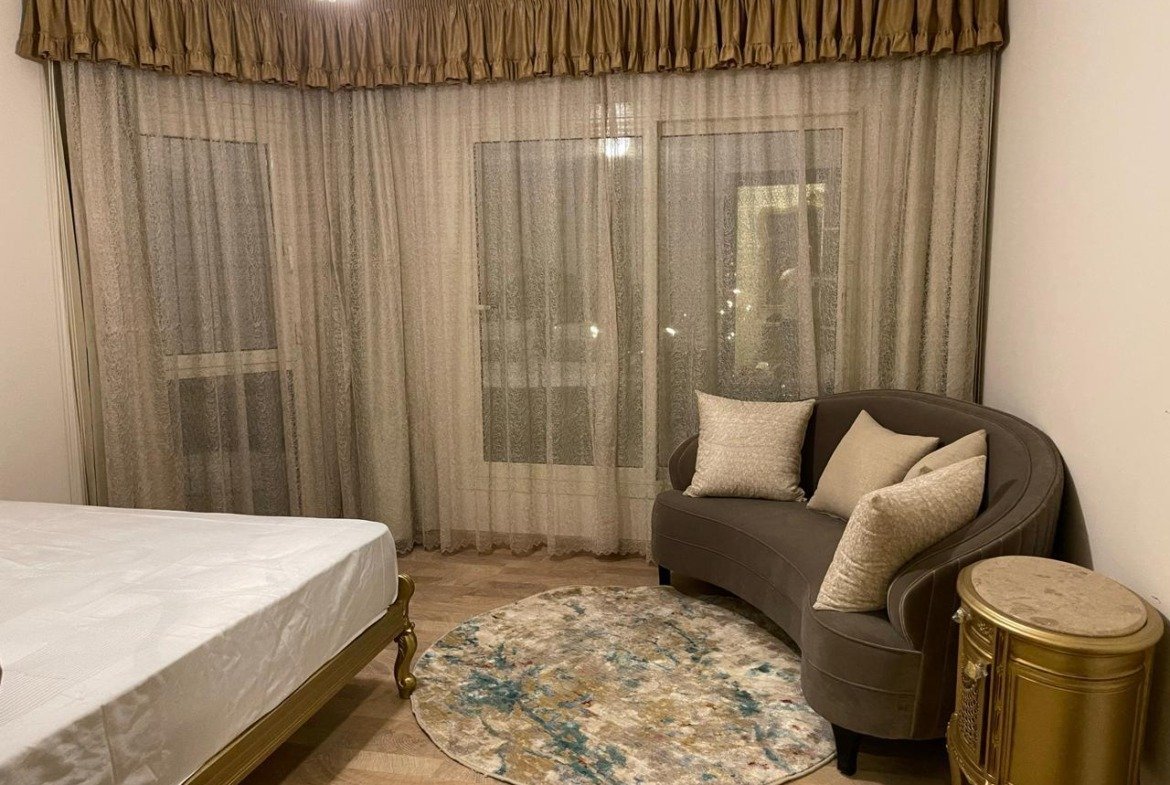 Bedroom with a curved armchair and a patterned rug - apartment in Akoya, New Cairo