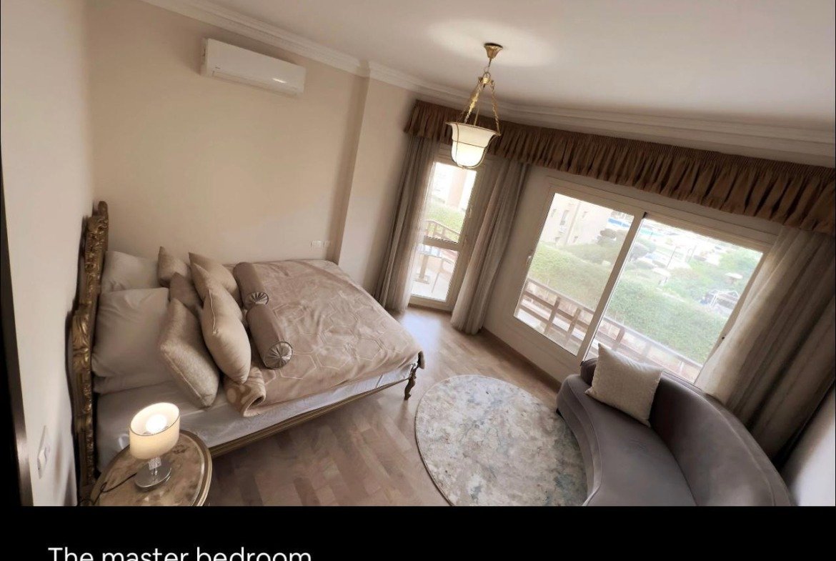 Bedroom with a double bed and a sitting area by the window - apartment in Akoya, New Cairo