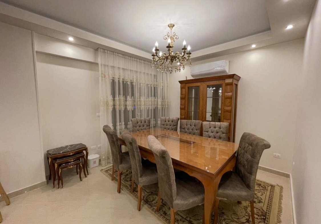 Dining room with a wooden table and a carved display cabinet - apartment in Akoya, New Cairo