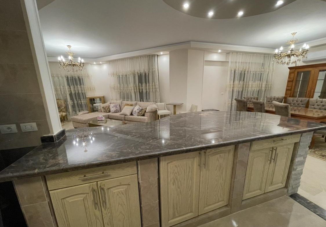 Kitchen island with cream cabinet doors facing the reception - apartment in Akoya, New Cairo