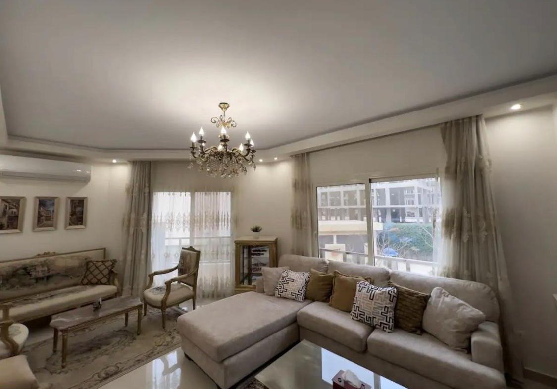 Living room with a corner sofa and a chandelier - apartment in Akoya, New Cairo