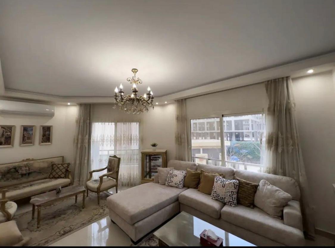 akoya-513-8 Living room with a corner sofa and a chandelier - apartment in Akoya, New Cairo
