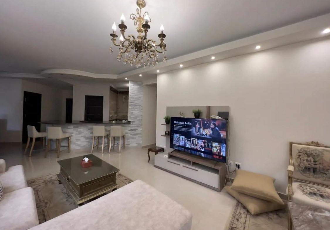 Reception with a wall-mounted TV and a coffee table - apartment in Akoya, New Cairo