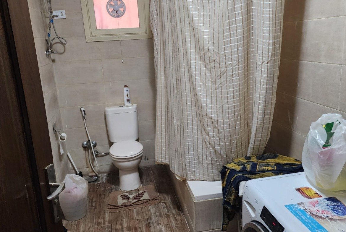 Bathroom with a shower curtain and a washing machine - apartment in Al Narges, New Cairo