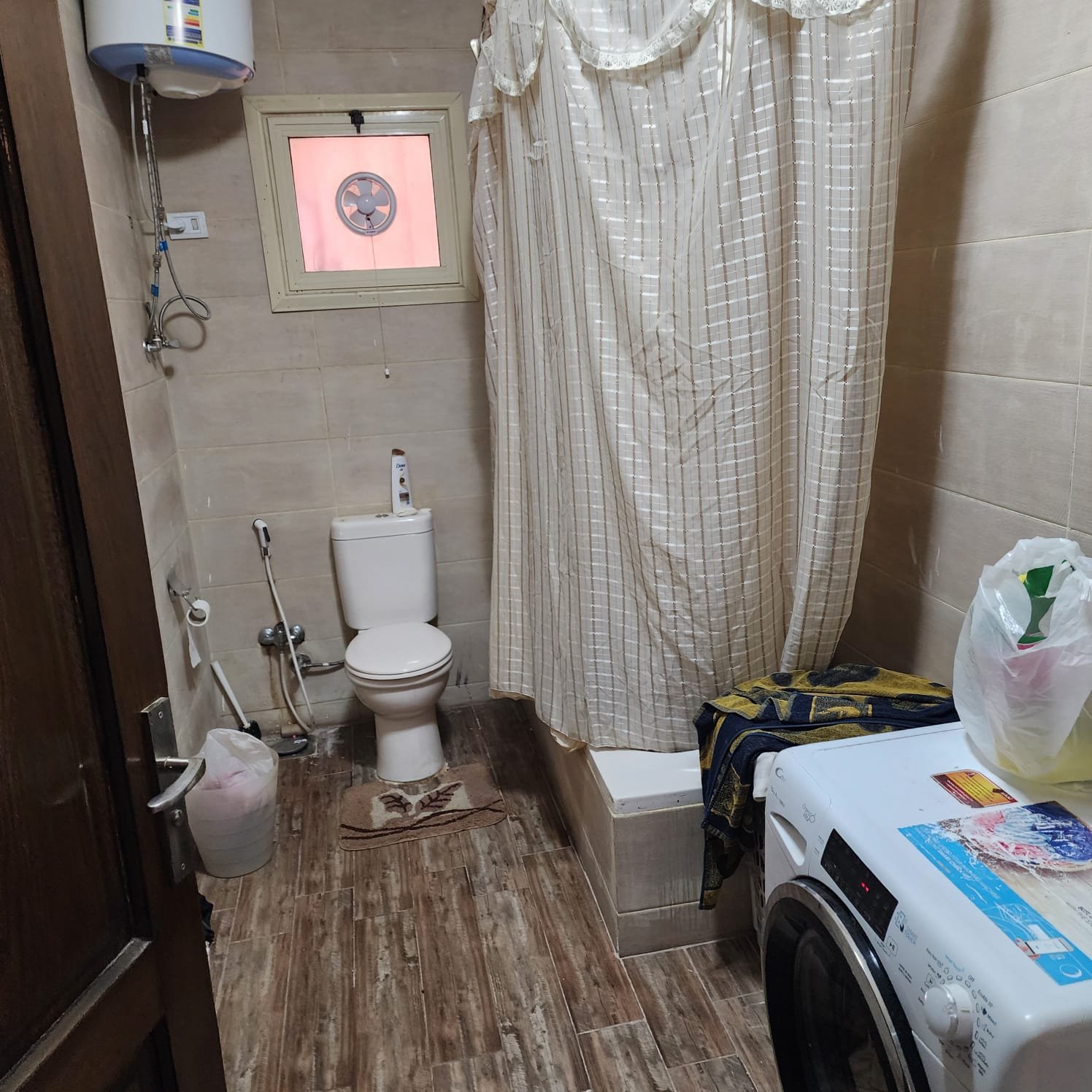 Bathroom with a shower curtain and a washing machine - apartment in Al Narges, New Cairo