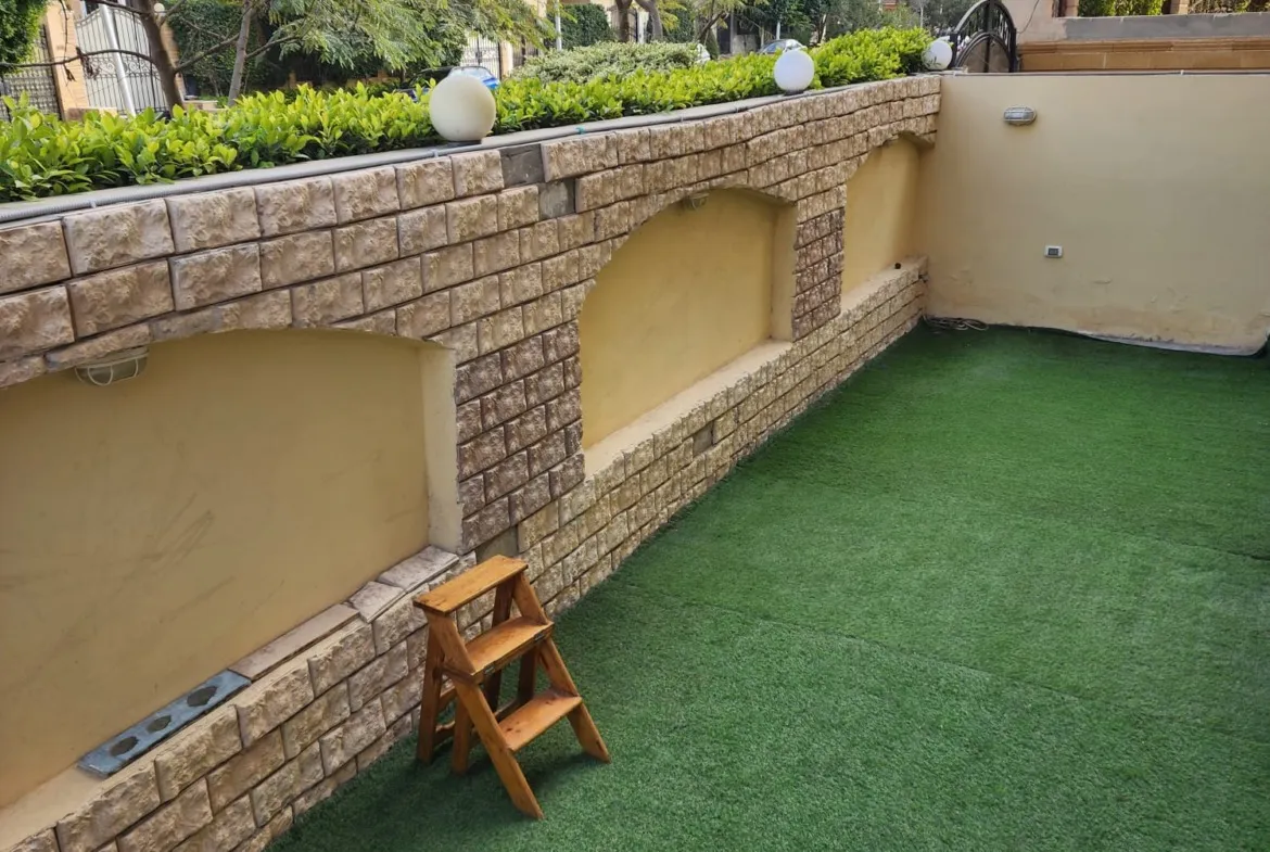 Private garden terrace with artificial grass and a stone wall - apartment in Al Narges, New Cairo