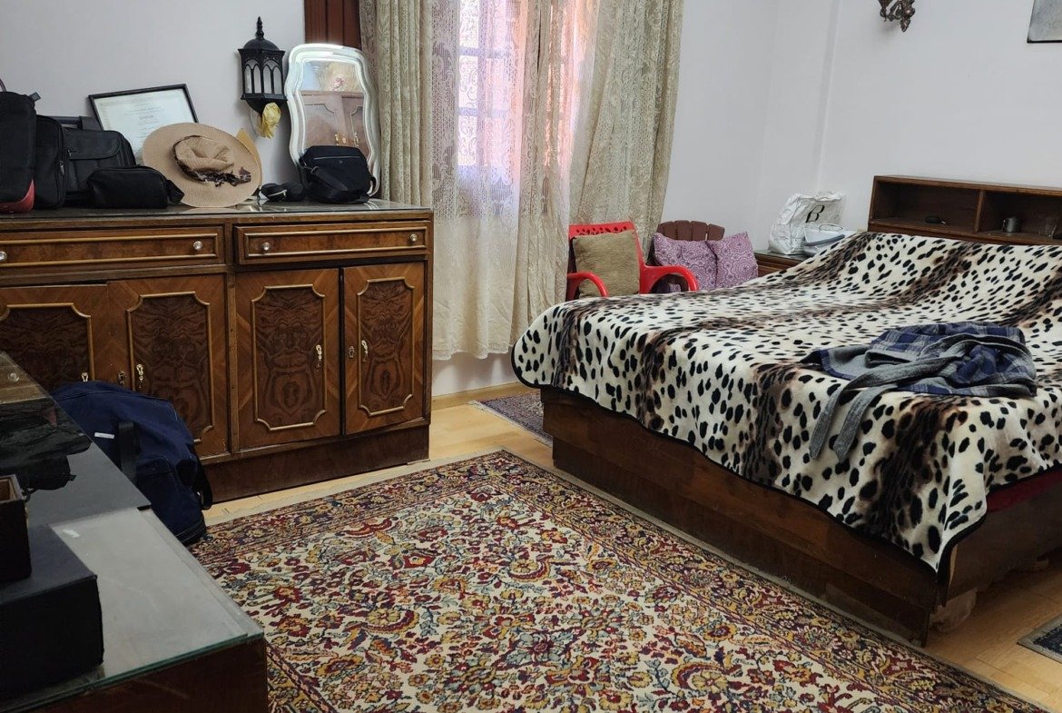 Master bedroom with a patterned bedspread and a carved dresser - apartment in Al Narges, New Cairo