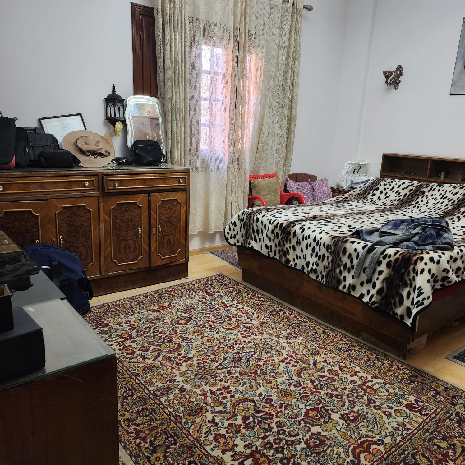 Master bedroom with a patterned bedspread and a carved dresser - apartment in Al Narges, New Cairo