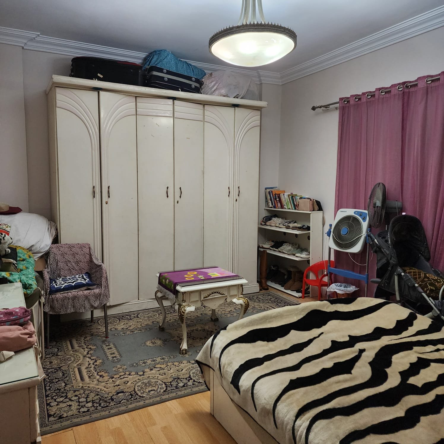 Bedroom with a tall white wardrobe and a striped bed cover - apartment in Al Narges, New Cairo