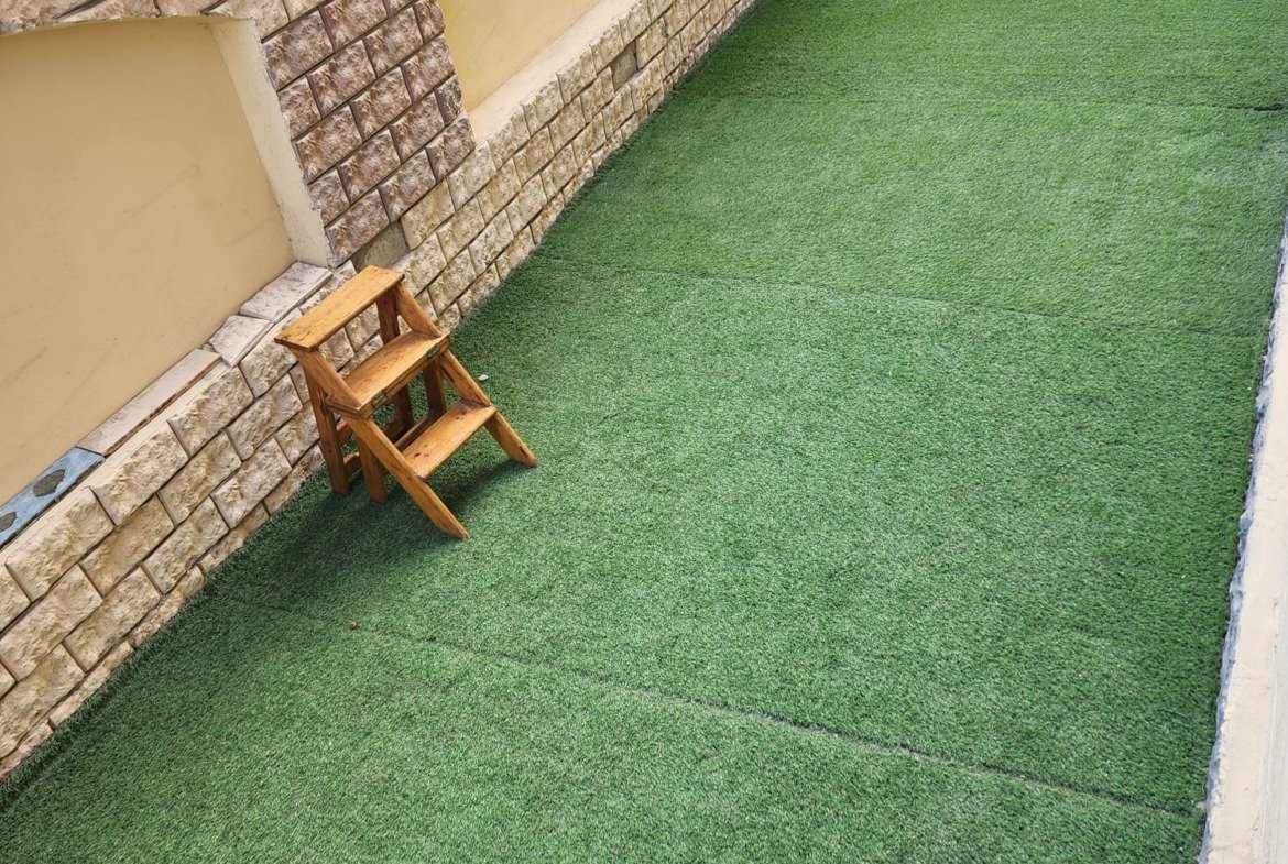 Strip of artificial grass with a small wooden step ladder - apartment in Al Narges, New Cairo