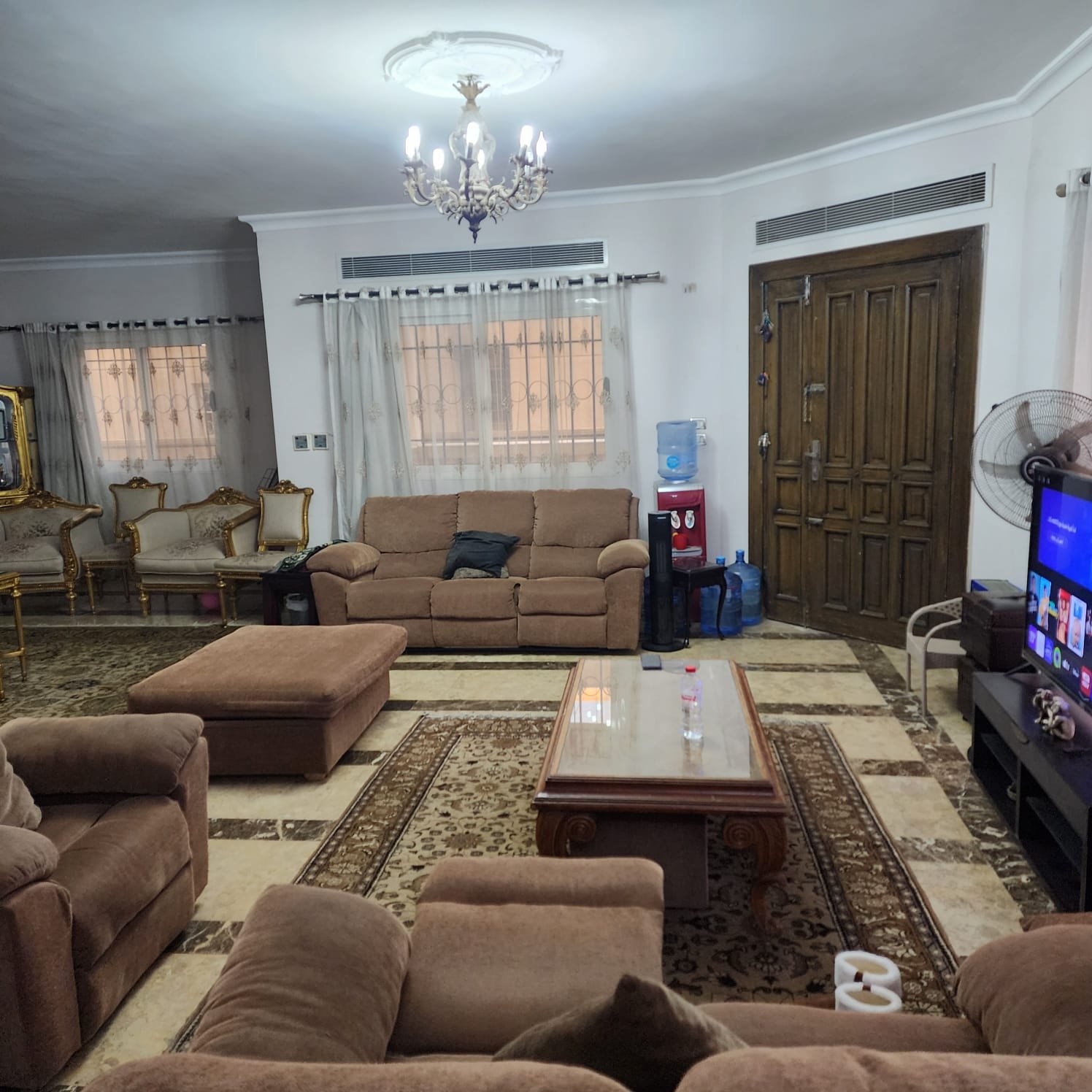 Large reception with brown sofas and a wooden entrance door - apartment in Al Narges, New Cairo
