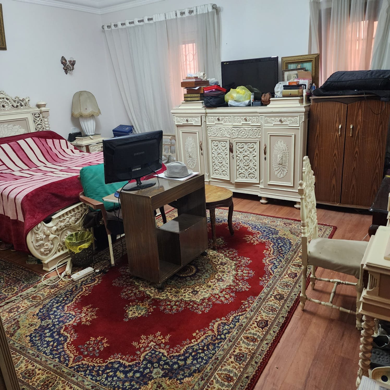 Bedroom with a red rug, a work desk and a white dresser - apartment in Al Narges, New Cairo