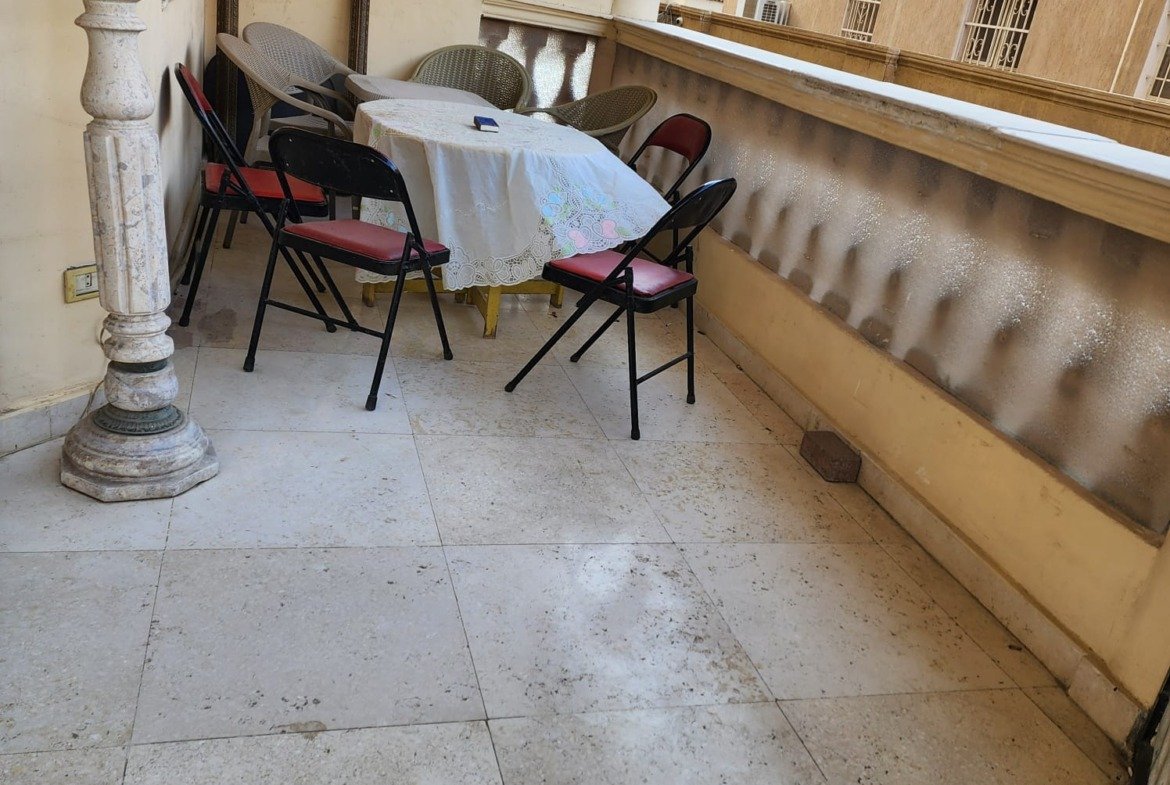 Covered balcony with a small table and folding chairs - apartment in Al Narges, New Cairo